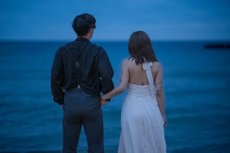 青い夕暮れの海で肩を寄せるふたり
